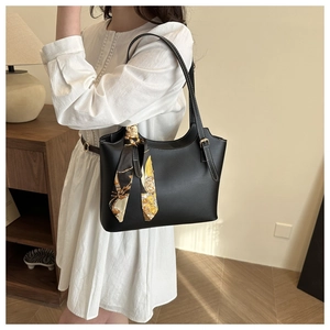 Detail of black matte leather tote bag featuring contrast stitching and floral silk scarf decor