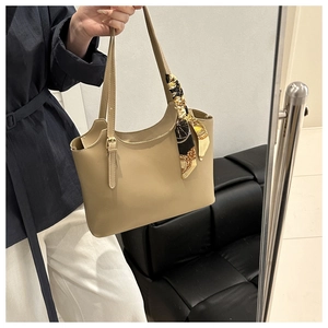 Detail of a khaki tote bag featuring a floral silk scarf handle and metallic buckles