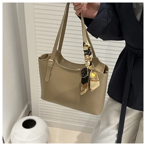 Detail of khaki tote bag with dual straps and decorative printed silk scarf on the handle