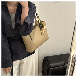 Detail of khaki leather tote bag with elegant patterned silk scarf tied on the handle
