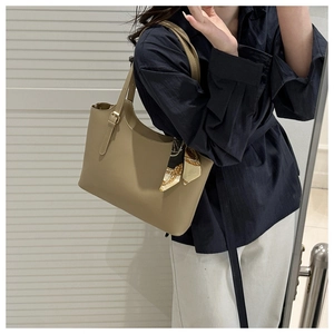 Khaki tote bag with printed silk scarf detail styled on a model in a minimal setting