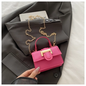Detail of rose pink mini bag with gold chain strap and U-shaped buckle on a grey blazer