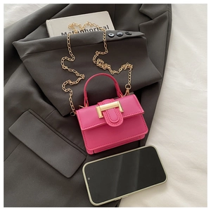 Detail of mini hot pink handbag with gold chain strap next to a smartphone