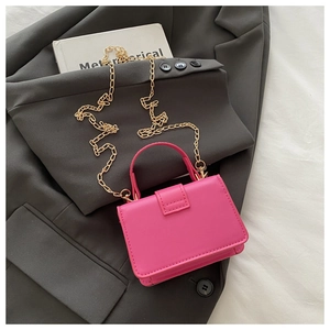 Detail of bright pink mini handbag with gold chain strap on dark grey blazer background