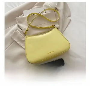 Detail der hellgelben sichelförmigen Schultertasche mit FASHION-Schriftzug im Fokus