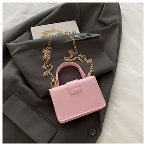 Pink mini leather crossbody bag with gold chain strap on grey blazer background