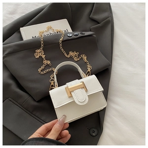 Close-up of white leather handbag with gold buckle and chain on grey blazer background
