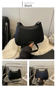 Detailansicht der schwarzen Schultertasche mit goldener Aufschrift und verstellbarem Gurt