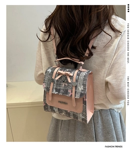 Detail of tweed backpack featuring a pink bow and heart pendant on the front pocket
