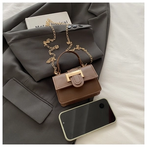 Detailed close-up of mini brown PU leather handbag with gold chain and U-shaped buckle