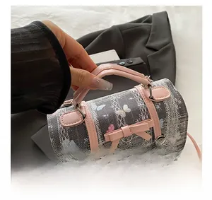 Detail of grey mesh handbag with pink leather trim, bow decoration, and heart pendant