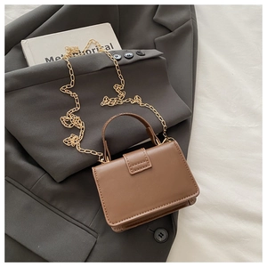 Detailed view of a brown leather mini flap bag with a gold chain on a grey blazer