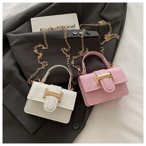Dettaglio mini borse a tracolla bianche e rosa con catena dorata su blazer grigio