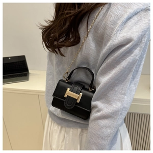 Detail of mini black leather handbag featuring golden H-clasp and metallic chain strap