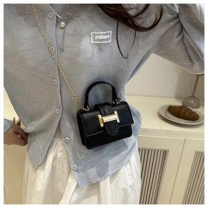 Detail of a chic black leather crossbody bag with elegant gold chain and top handle strap