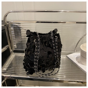 Détail du sac seau à paillettes noires avec chaîne argentée sur étagère