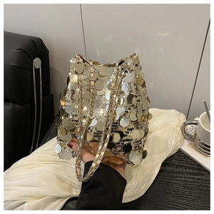 Gros plan d'un sac seau doré à paillettes avec une bandoulière chaîne élégante