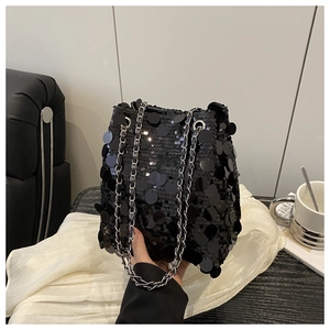 Détail d'un sac seau chic à paillettes noires avec bandoulière chaîne argentée brillante