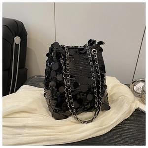 Détail d'un sac seau noir à paillettes avec une bandoulière chaîne argentée et texture chic