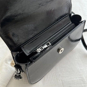 Black minimalist square saddle bag with silver magnetic buckle and polished leather texture