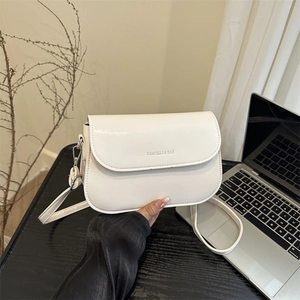 Minimalist white leather saddle crossbody bag with a flap cover and branded detail