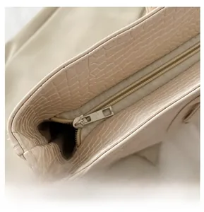 Detail view of smooth metal zipper and premium crocodile pattern leather on tote bag