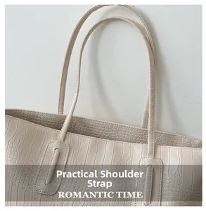 Detail of wide reinforced shoulder straps on cream crocodile embossed tote bag