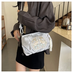 Gedetailleerd borduurwerk van goudkleurige bloemen op zilverrijze fluwelen crossbody tas