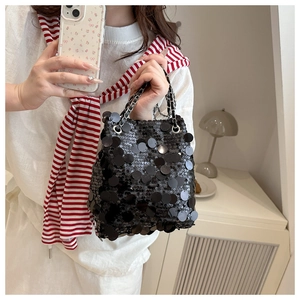 Détail de paillettes noires scintillantes et d'une bandoulière en chaîne argentée tissée