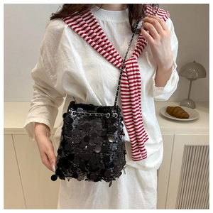 Detailed close-up of a black sequin bucket bag with a chain strap in a stylish home setting