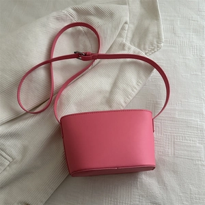 Sac seau minimaliste en cuir PU rose avec bandoulière réglable sur fond blanc texturé