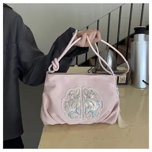 Ricamo dettagliato e nappa di seta su una borsa rosa in stile cinese con motivi floreali