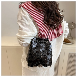 Détail d'un sac seau noir à paillettes avec bandoulière chaîne argentée porté par un mannequin