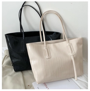 Detail of crocodile pattern tote bags in black and beige leaning against a wall