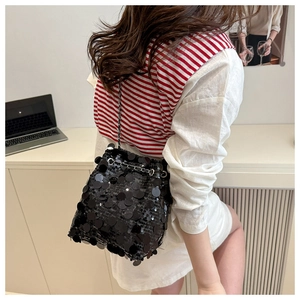 Détail du sac seau noir à paillettes avec bandoulière chaîne porté à l'épaule