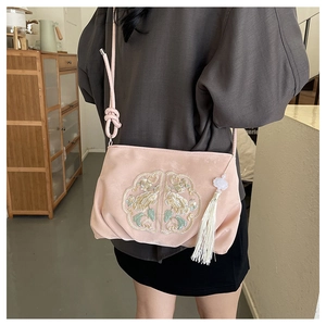 Detail van roze geborduurde tas met bloemmotieven en witte bloem kwastje hanger decoratie