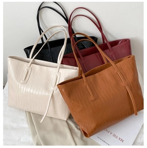 Detail view of large tote bags in multiple colors with embossed crocodile pattern texture
