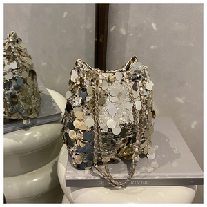 Vue détaillée d'un sac seau à paillettes avec bandoulière chaîne sur un piédestal blanc