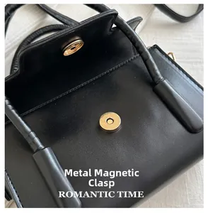 Detail der schwarzen Ledertasche mit hellem Gold-Magnetverschluss und feinen Nähten