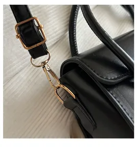 Details von goldenen Metallhaken und verstellbarem Schultergurt an schwarzer Ledertasche