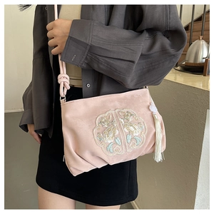 Dettaglio ricamo su borsa a tracolla in raso rosa con nappa di perle bianche e fili dorati