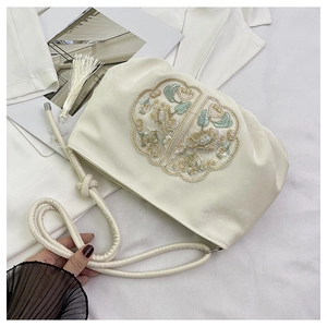 Dettaglio della borsa in raso crema con ricamo floreale e nappe eleganti decorative