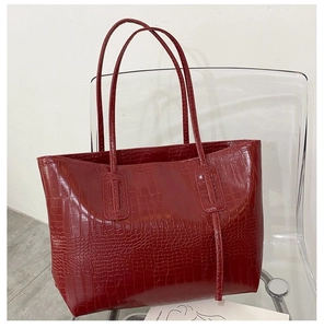 Macro shot of red crocodile embossed texture on a large stylish PU leather tote bag