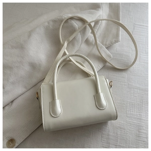 Top-down view of cream leather square bag with top handle and gold metal hardware clips