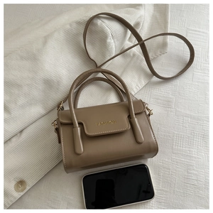 Detail of khaki crossbody bag with FASHION lettering and top handles on fabric