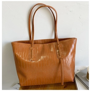 Close-up of the vintage crocodile embossed texture on the brown leather tote bag