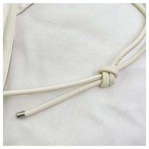 Dettaglio della tracolla in pelle bianco sporco con nodo e punte in metallo argentato