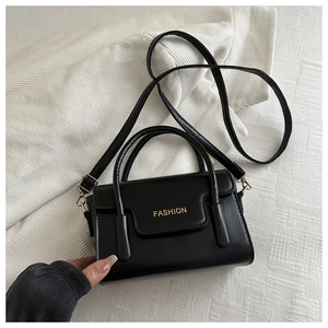 Detail of black leather square bag with gold FASHION text and elegant metal hardware
