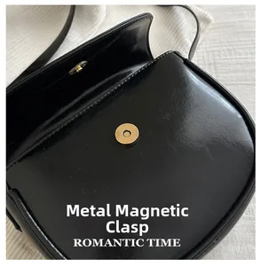 Detail of the high-gloss black leather bag showing the golden magnetic snap closure