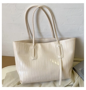 Close-up of cream crocodile pattern tote bag featuring long vertical decorative straps